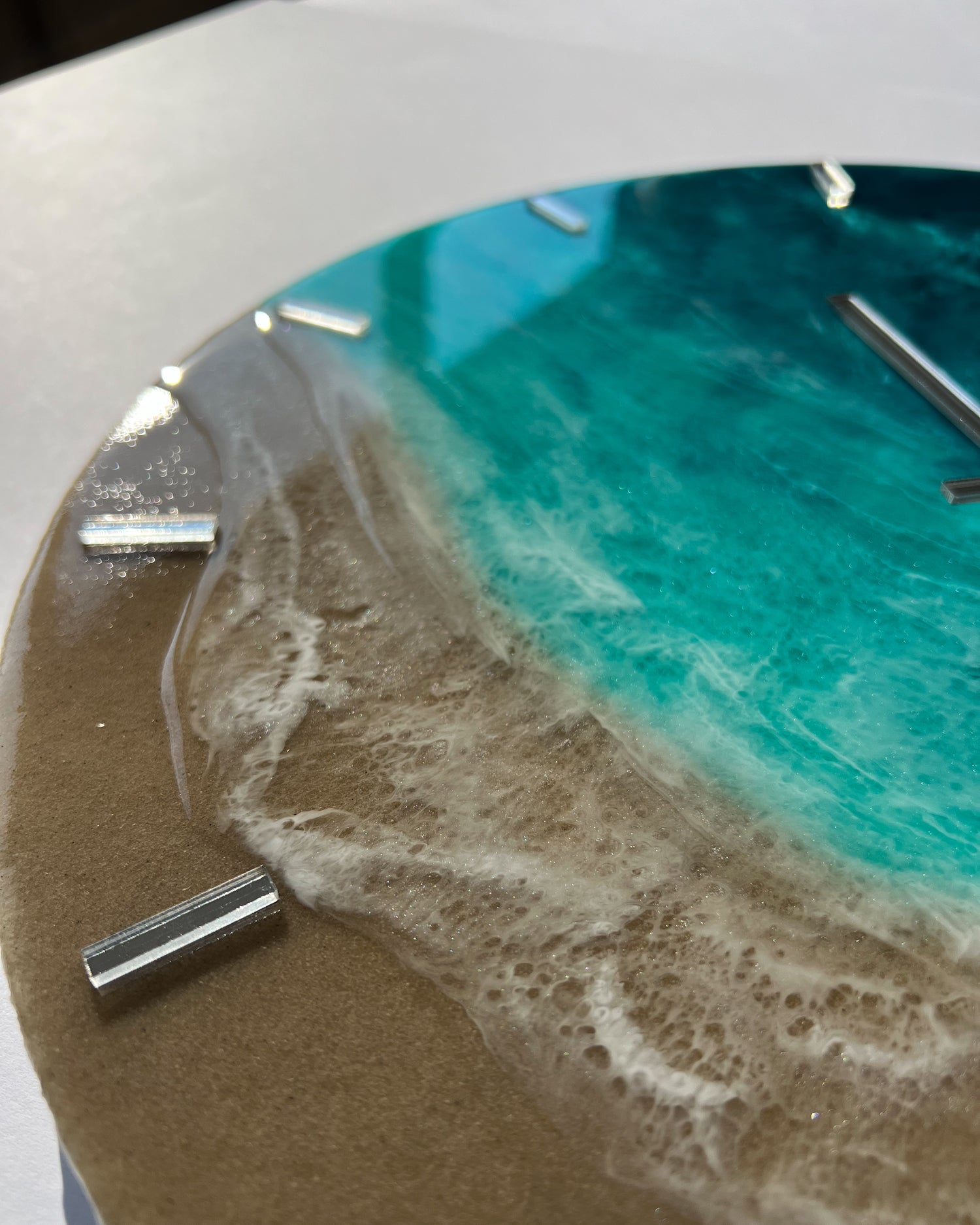 Epoxigyanta falióra türkiz és mélykék óceánhatású mintázattal, fehér habos hullámokkal és homokszínű parttal, közelről fotózva.